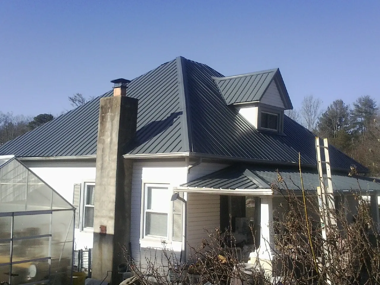 Dark blue standing seam metal roof on a white farmhouse with dormer — Slate & Tile Roof Repair by Roofing Brothers in Aberdeen Proving Ground