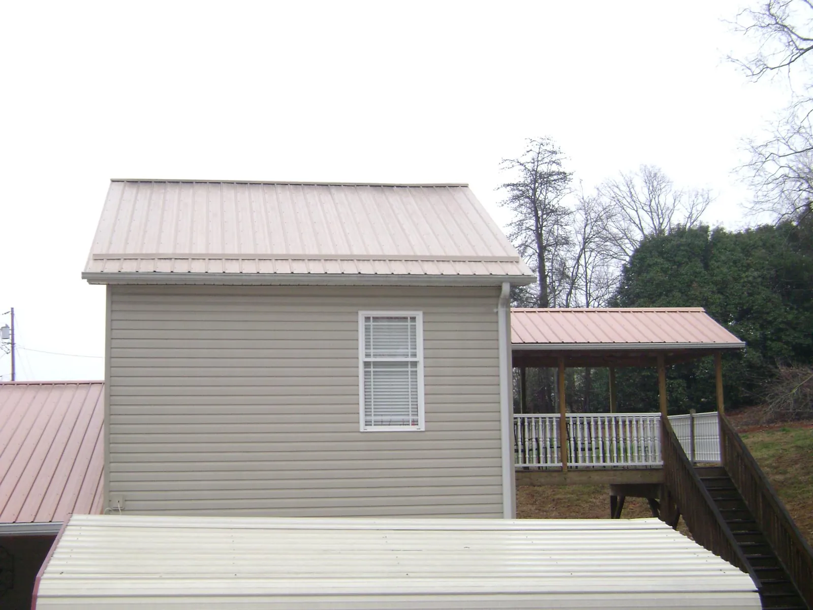 Tan metal roofs on a two story addition and attached porch, from a Roof Replacement job in Aberdeen Proving Ground