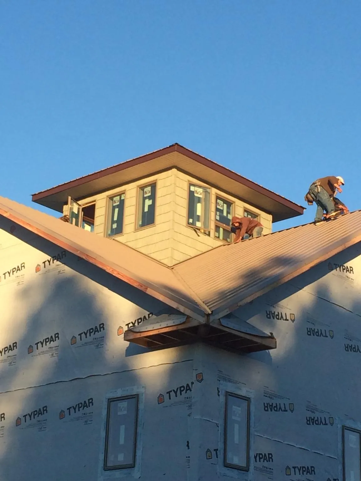 Roofers working around a rooftop cupola on a new metal roof at sunset — Roof Waterproofing in Aberdeen Proving Ground by Roofing Brothers